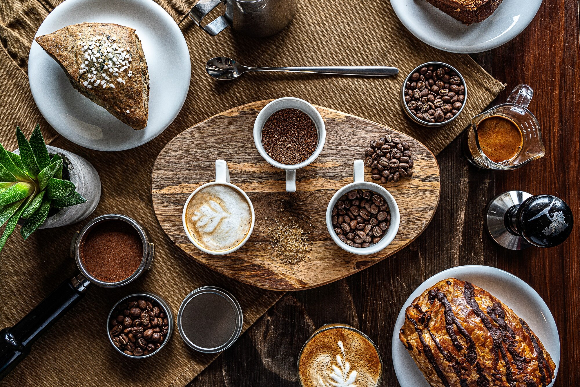 high-angle-shot-coffee-beans-jars-breakfast-table-with-some-pastry_181624-5864